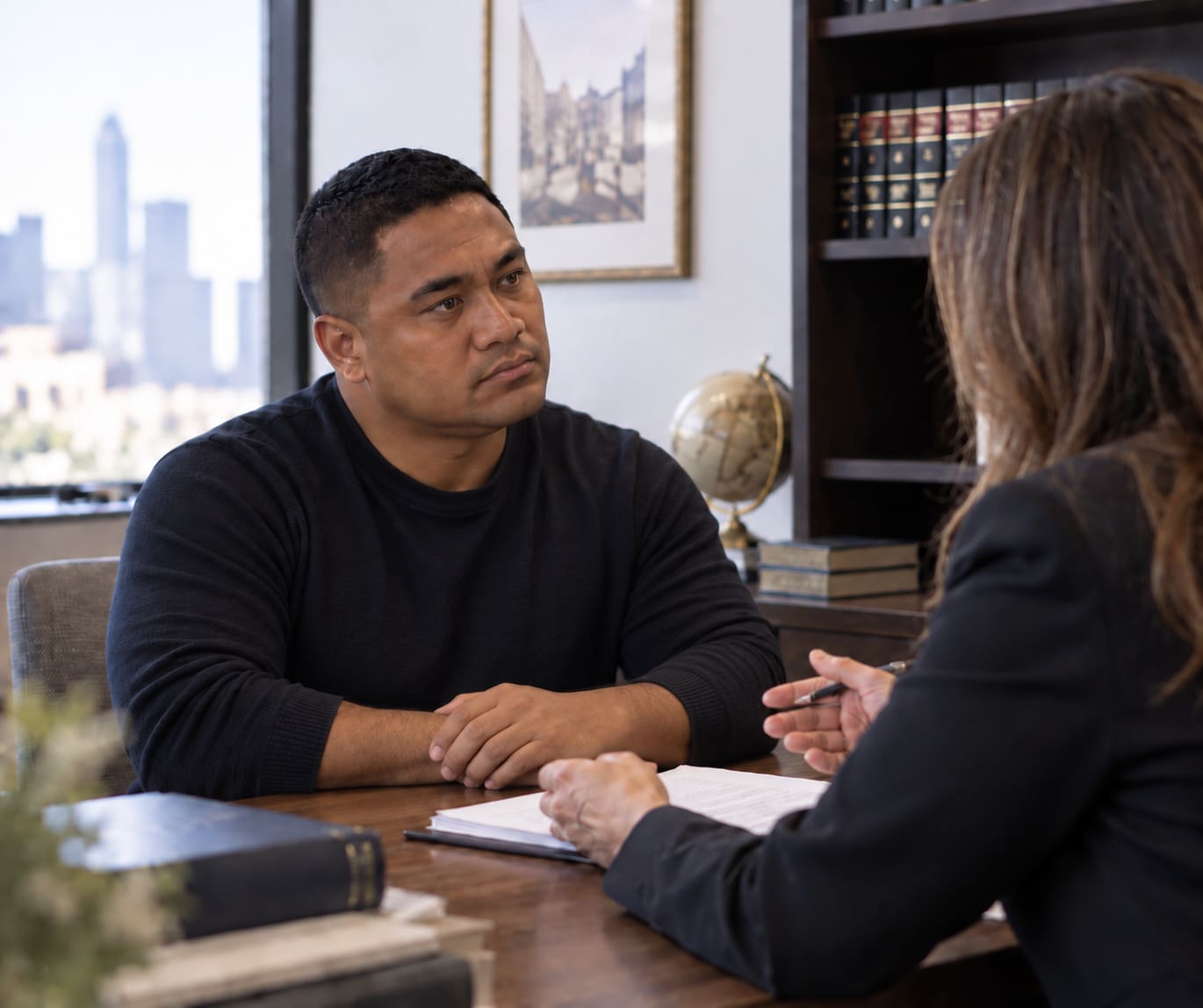 Man discussing documents with a professional across an office desk